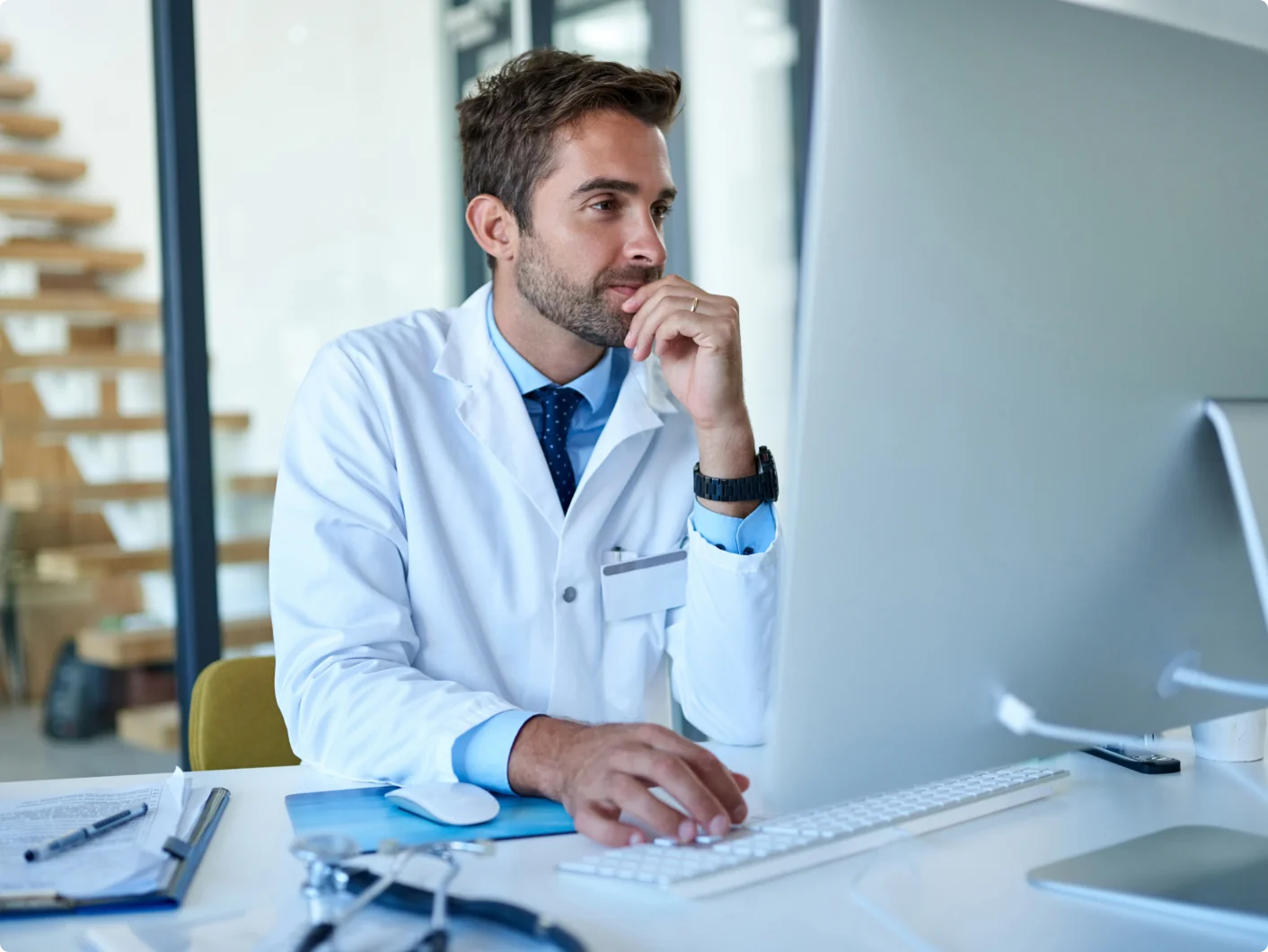 Physician reviewing patient information on a desktop computer