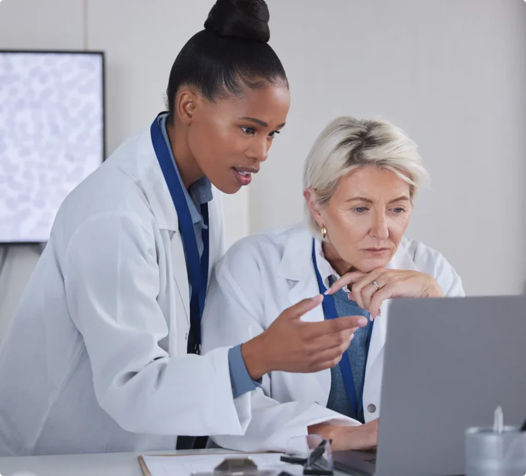 Two clinicians reviewing patient data on a laptop